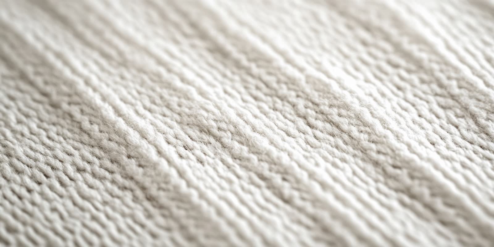 Cream wool knit in a diagonal ribbed stitch, soft fibres catching light across the raised rows.